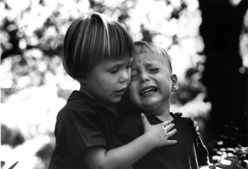 A child comforting another crying child. Black and white photo.