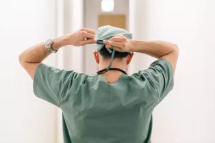 Surgeon in scrubs tying headscarf. Photo.